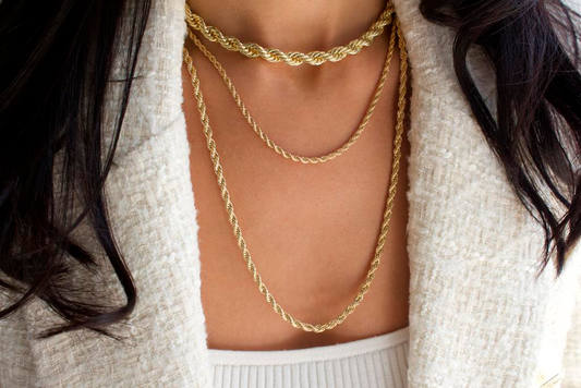 A woman wearing three layered gold rope chains of varying thicknesses with a tweed blazer.
