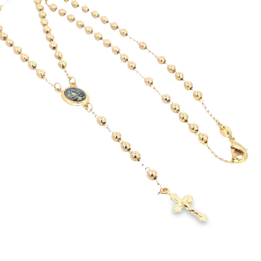 A delicate gold rosary necklace features polished bead stations, a small religious medallion, and a dangling crucifix.