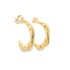 A pair of hammered gold hoop earrings rests against a white background.