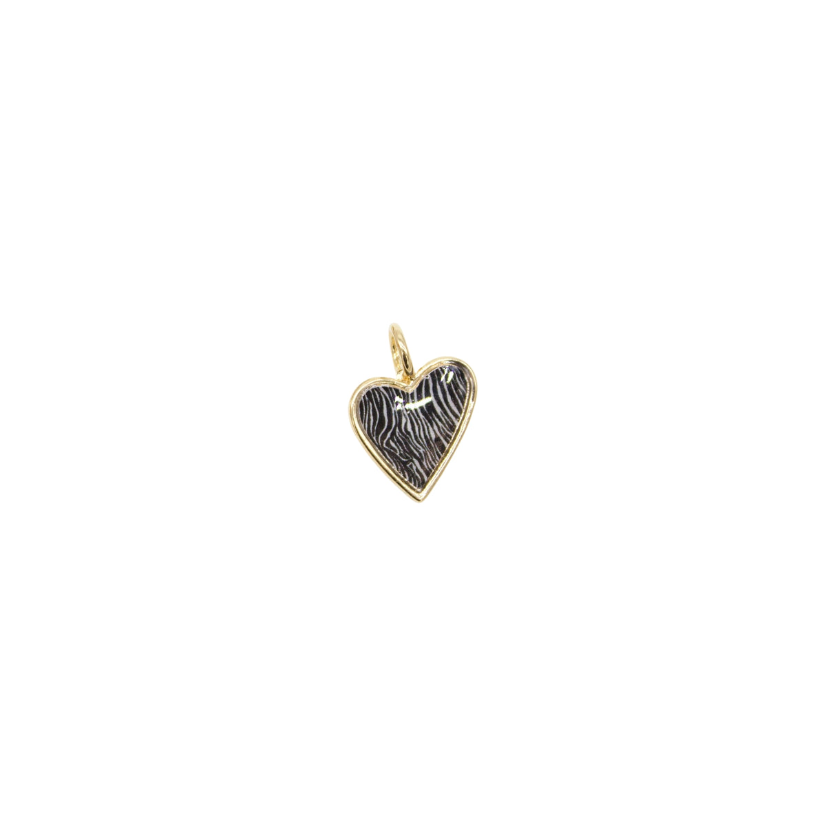 A gold heart charm featuring a black and white zebra print pattern rests isolated on a white background.