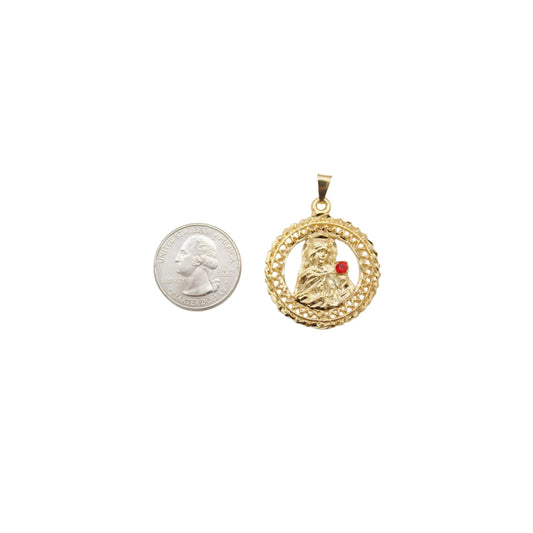 A round gold pendant featuring a depiction of the Virgin Mary with a red gemstone rests next to a US quarter coin for size comparison.