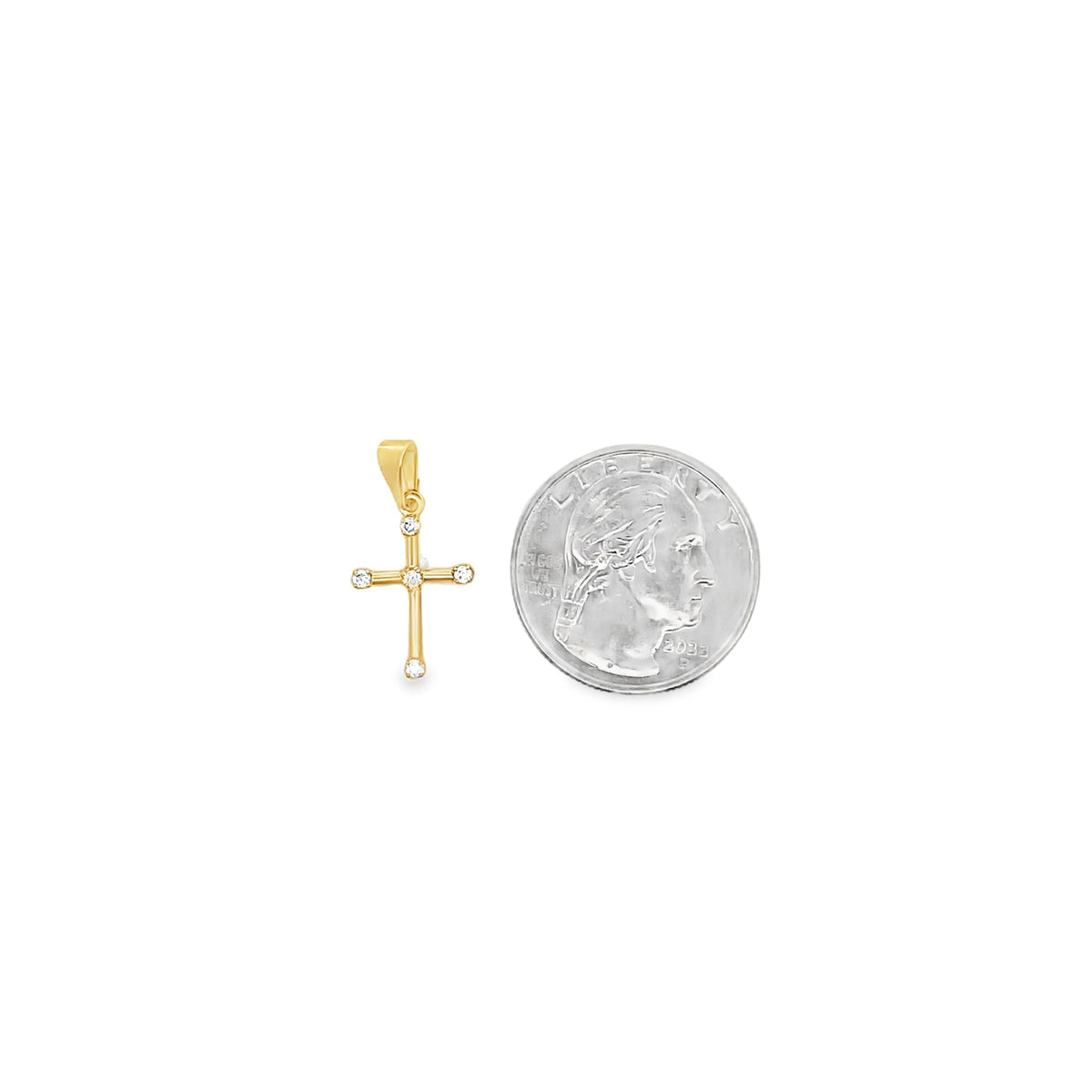 A delicate gold cross pendant featuring sparkling diamond accents rests next to a US quarter for size comparison.