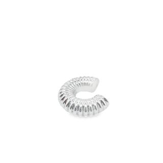 A ribbed silver ear cuff rests on a clean white surface.