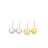A pair of silver ball drop earrings rests next to a matching pair of gold ball drop earrings against a plain white background.