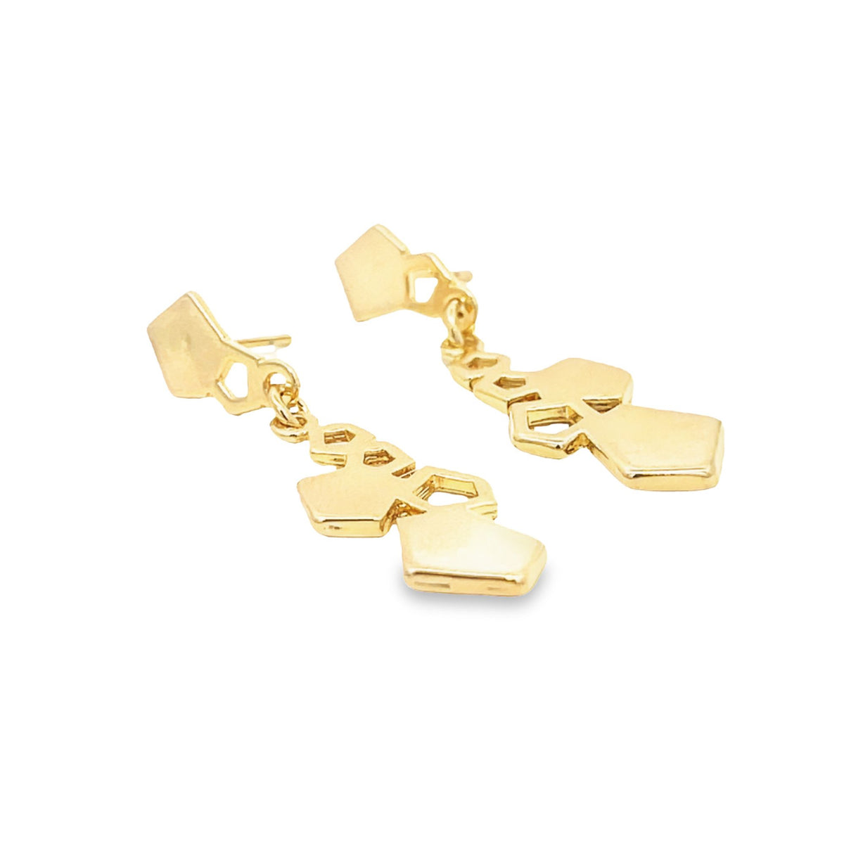 A pair of dangling gold geometric earrings resting on a white surface.