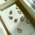 A collection of gold diamond-encrusted initial letter pendants rests neatly inside a white velvet jewelry box.