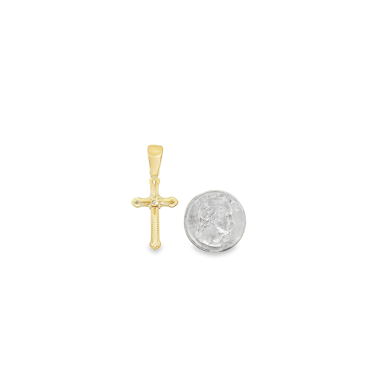 A gold cross pendant sits next to a US quarter coin to show its scale.