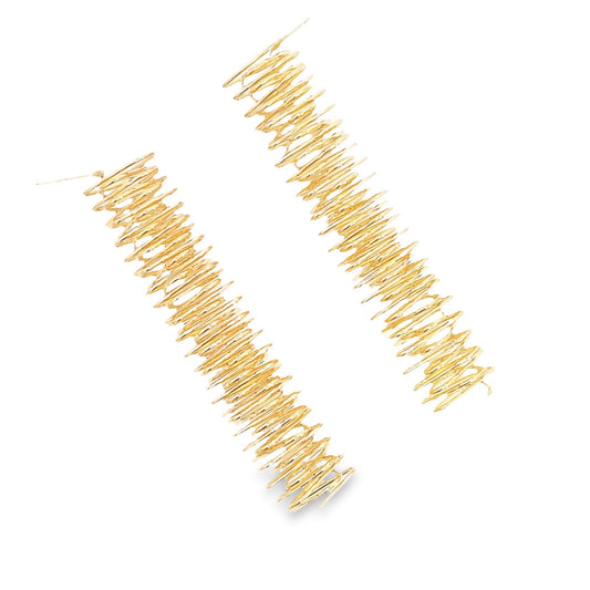 A pair of long, abstract textured gold dangle earrings resting diagonally against a clean white background.