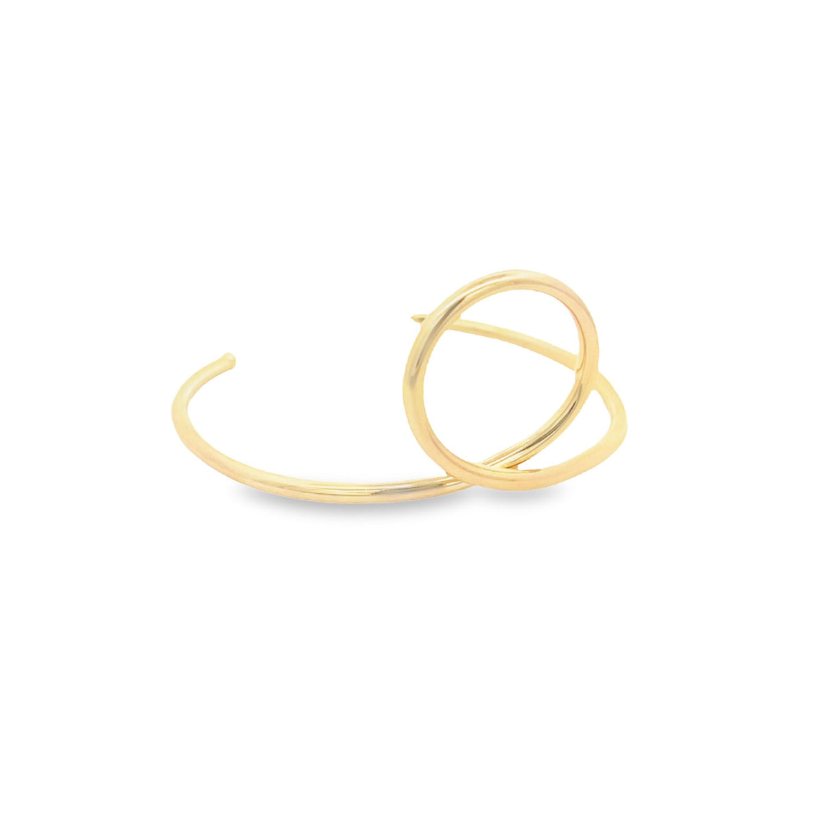 A modern gold cuff earring features a unique double-loop design resting on a white surface.