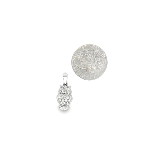 A sparkling white gold owl pendant rests next to a US quarter coin for size comparison.