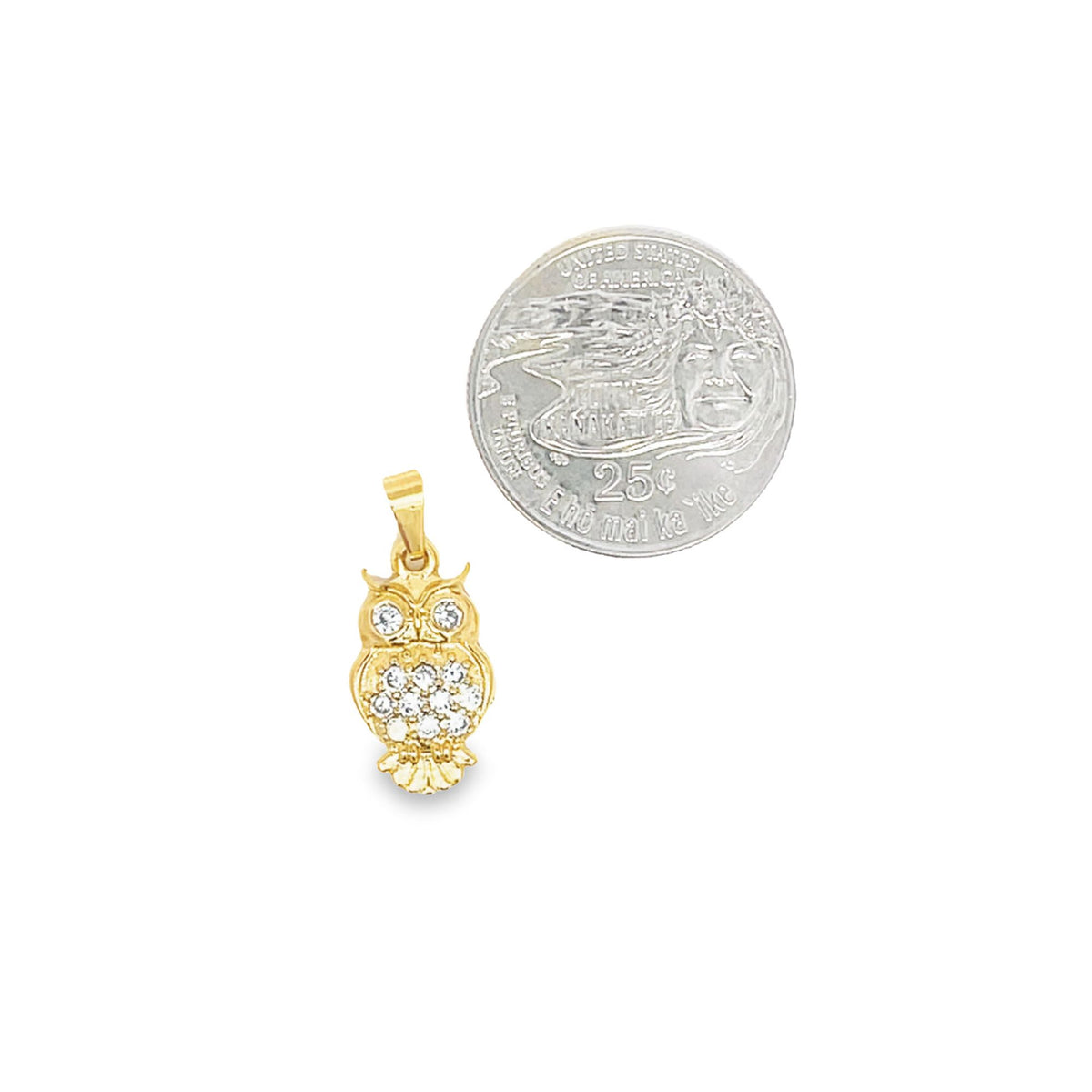 A small gold owl pendant rests beside a quarter to demonstrate its size.