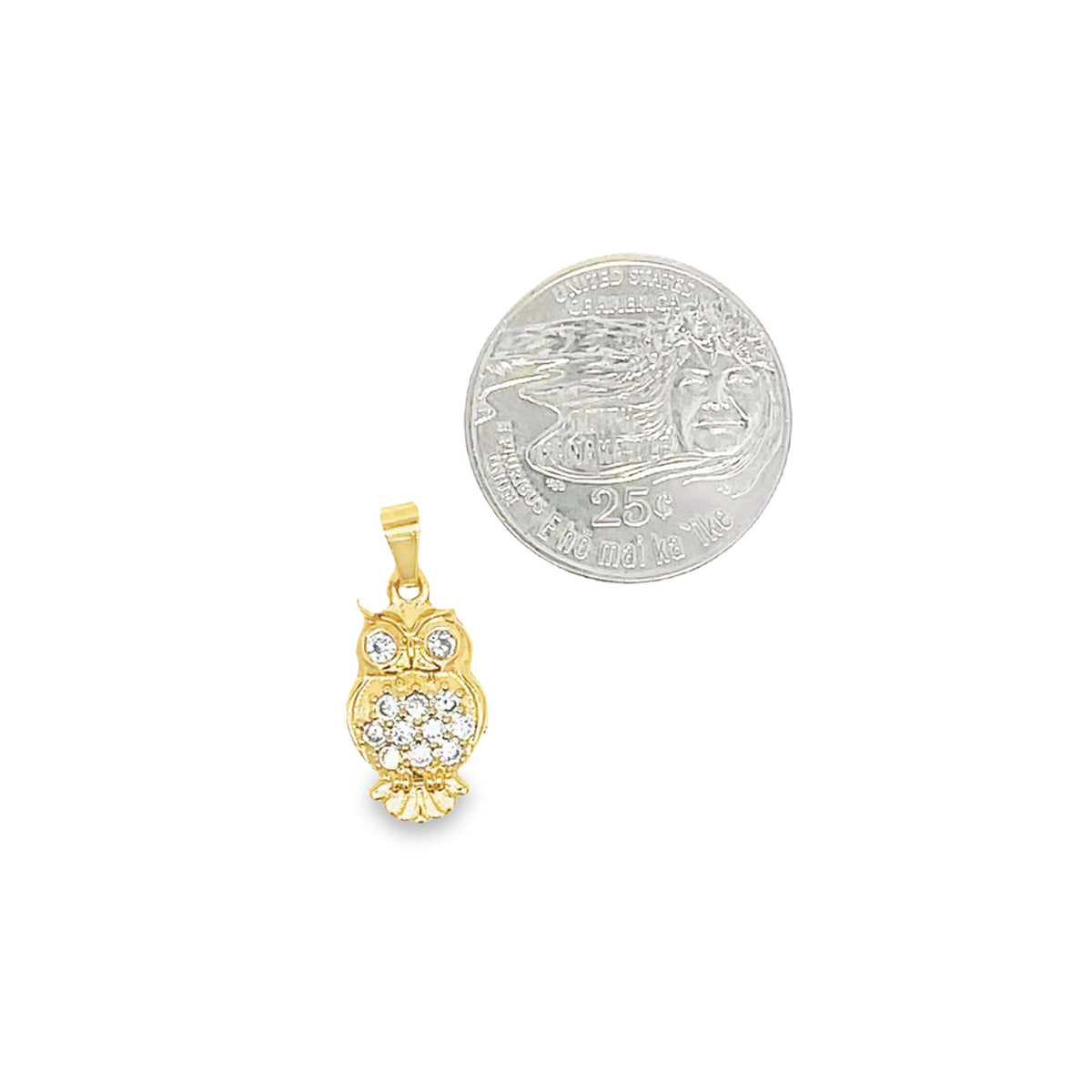 A gold owl pendant embellished with sparkling cubic zirconia stones rests beside a US quarter coin for scale.