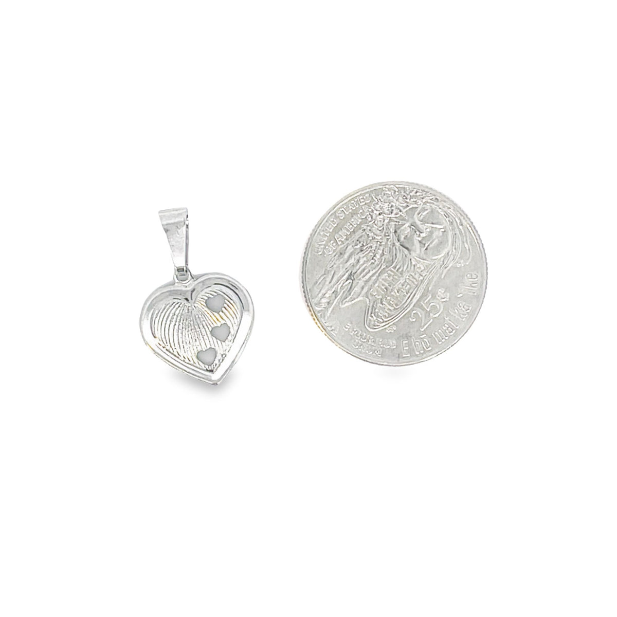 A silver heart pendant featuring a fingerprint design with three small hearts lies next to a US quarter coin for scale.