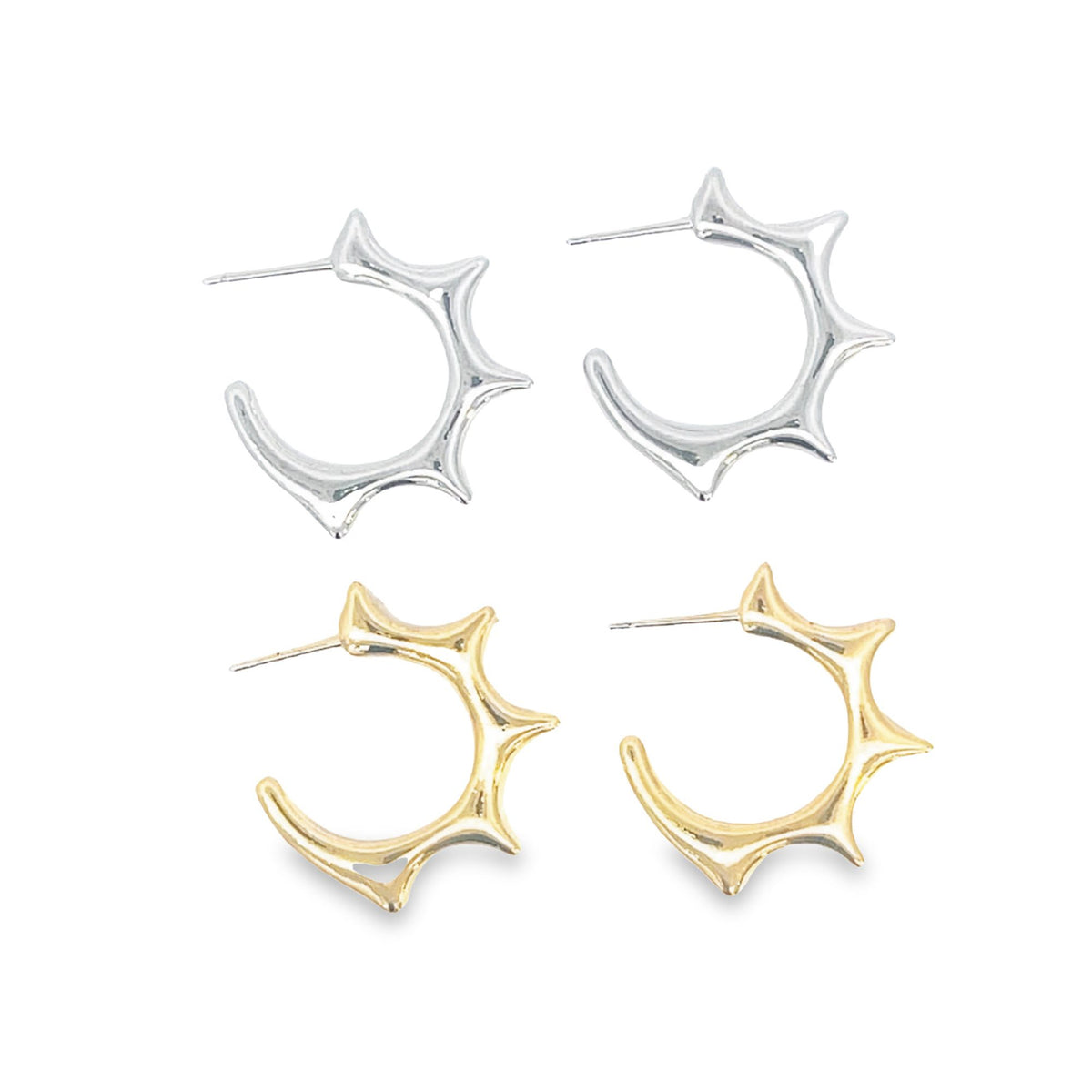 Two pairs of spike hoop earrings in polished silver and gold rest against a white background.