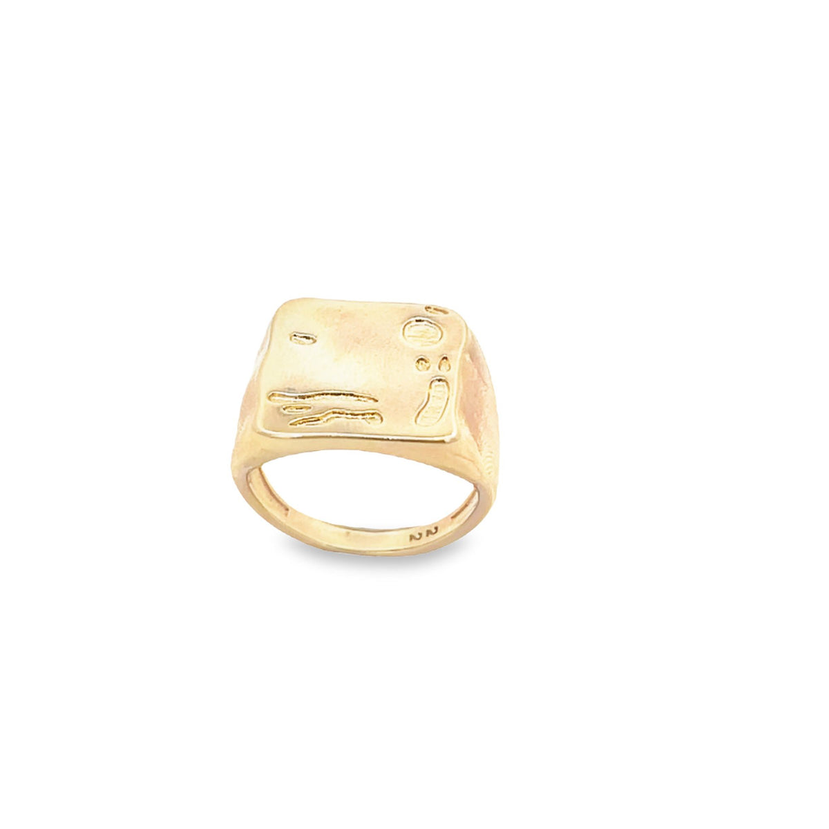 A gold signet ring featuring abstract engraved designs rests against a clean white background.