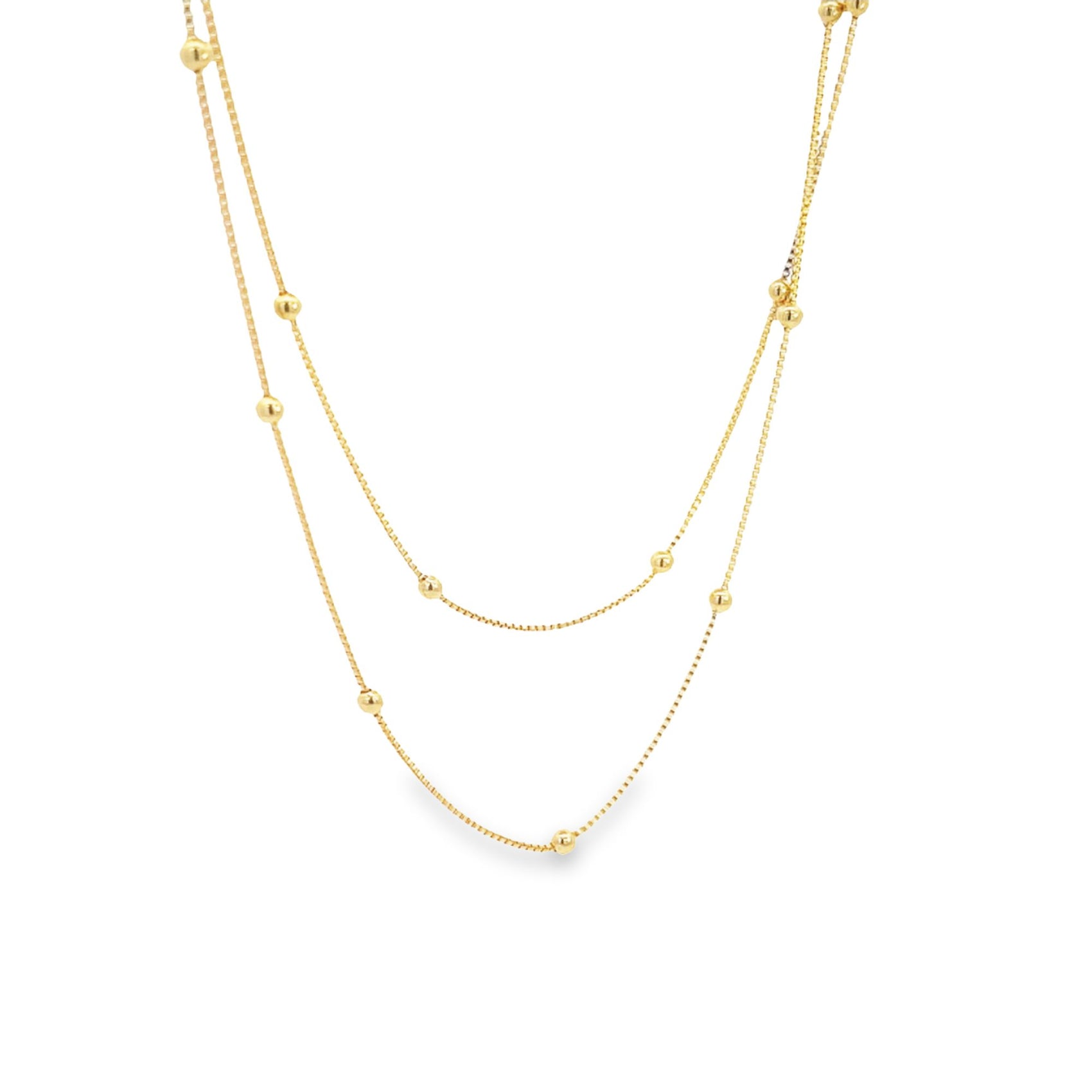 A delicate double-layered gold chain necklace features evenly spaced spherical beads along its thin links against a plain white background.