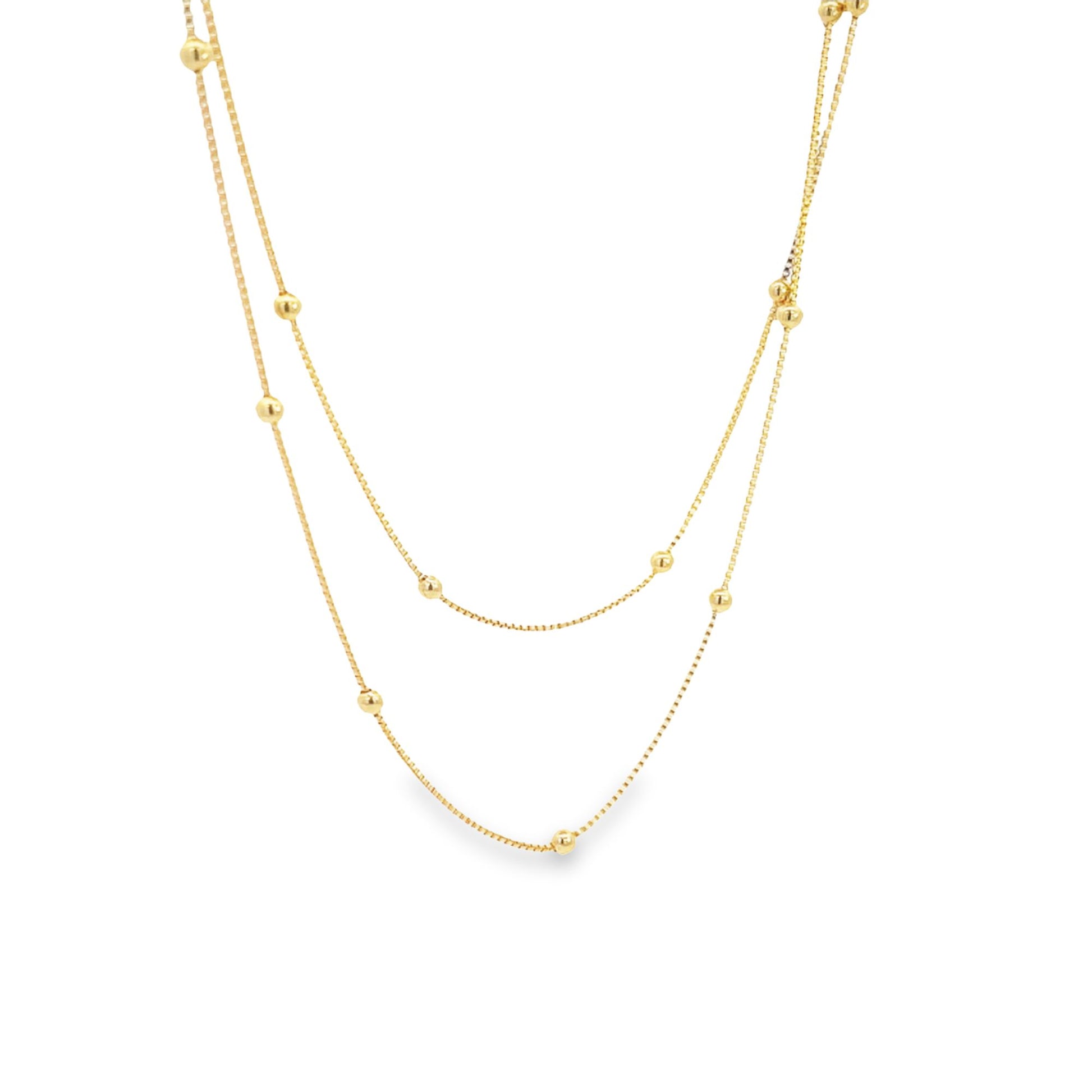 A delicate double-layered gold chain necklace features evenly spaced spherical beads along its thin links against a plain white background.