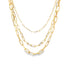 A layered gold paperclip chain necklace drapes elegantly against a white background.
