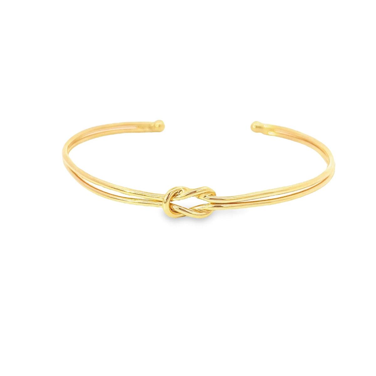 An elegant gold cuff bracelet features a delicate center knot design against a clean white background.