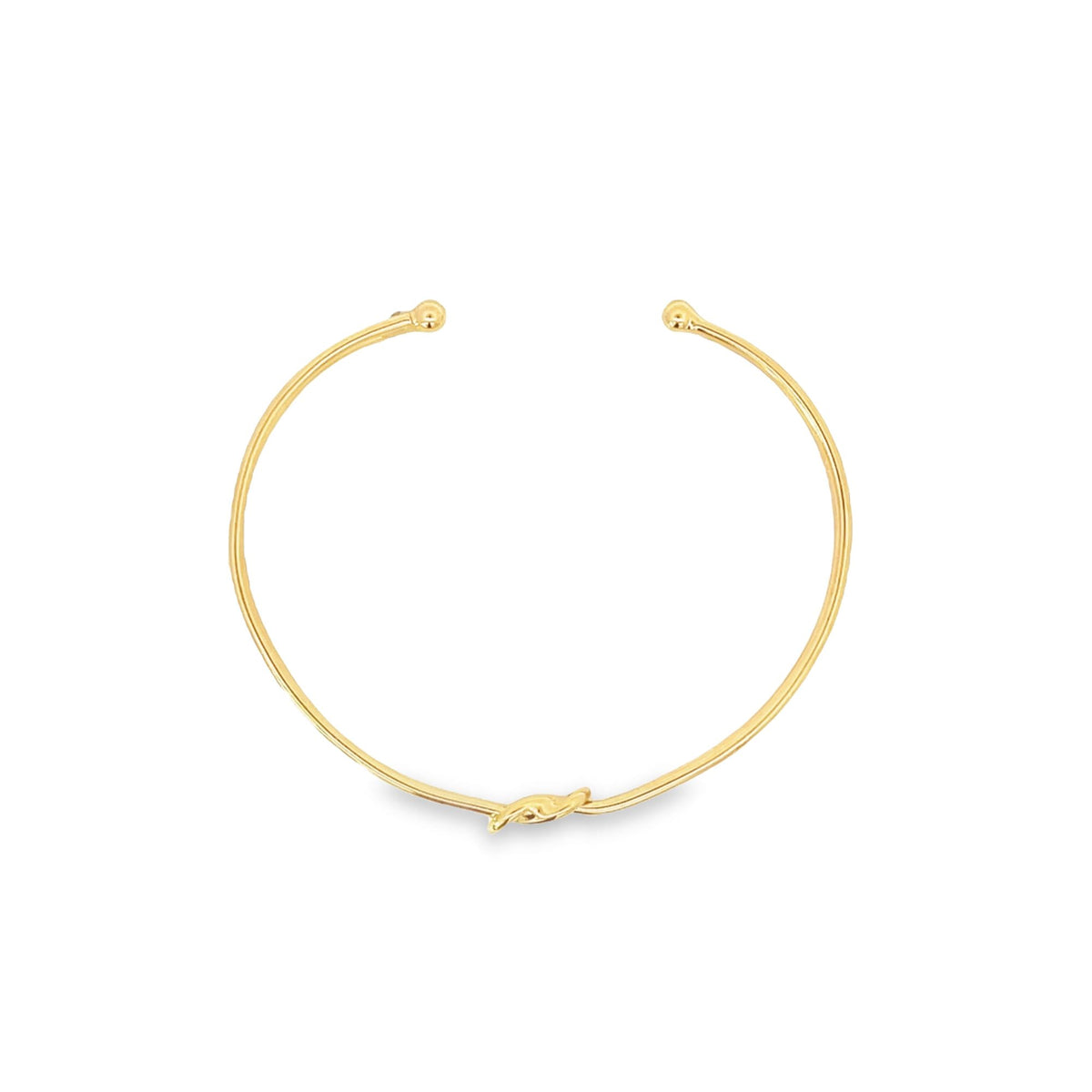 A gold open-cuff bracelet features polished ball terminals and a delicate central knot detail against a clean white background.