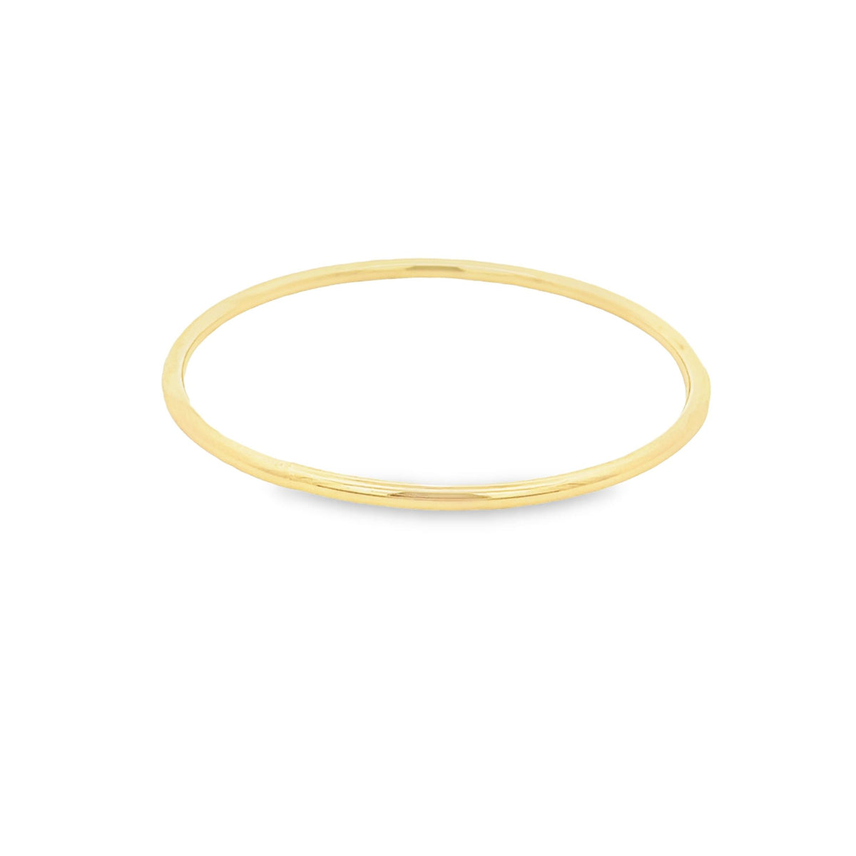 A thin gold stacking ring rests on a plain white surface.
