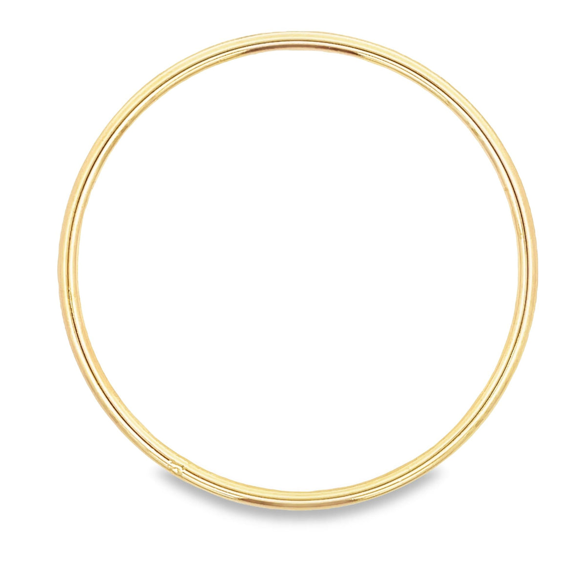 A shiny gold hoop earring rests on a white background, casting a soft shadow underneath.
