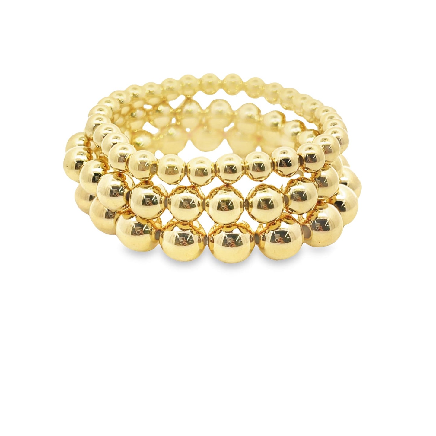 A stack of three shiny gold beaded bracelets rests against a plain white background.
