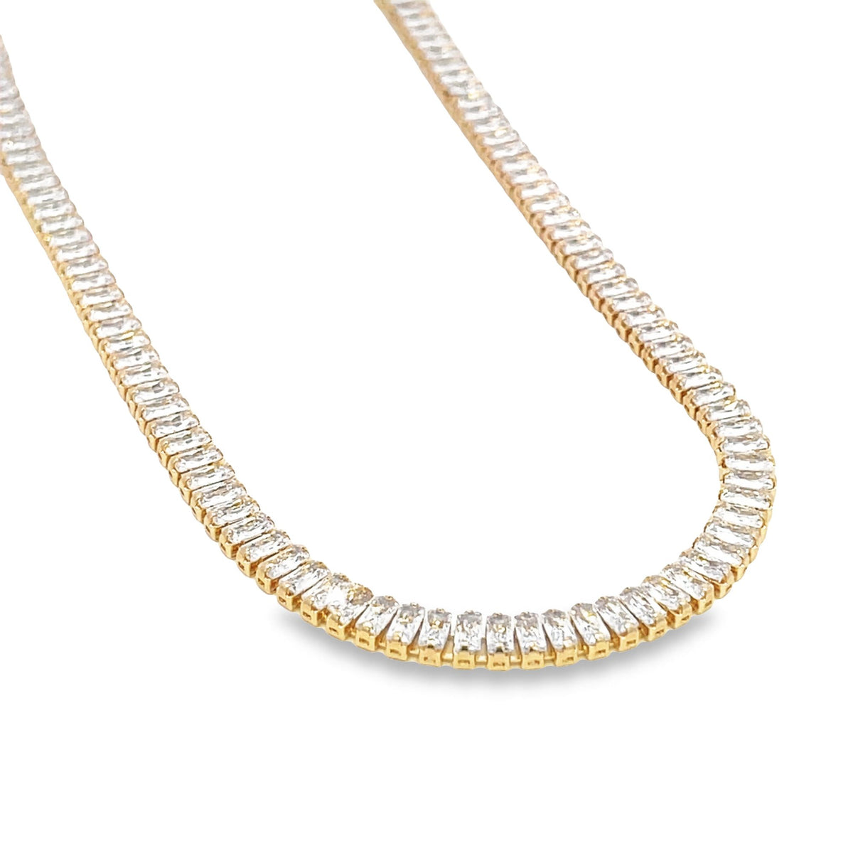 A gold tennis necklace features a continuous row of sparkling baguette-cut diamonds against a clean white background.