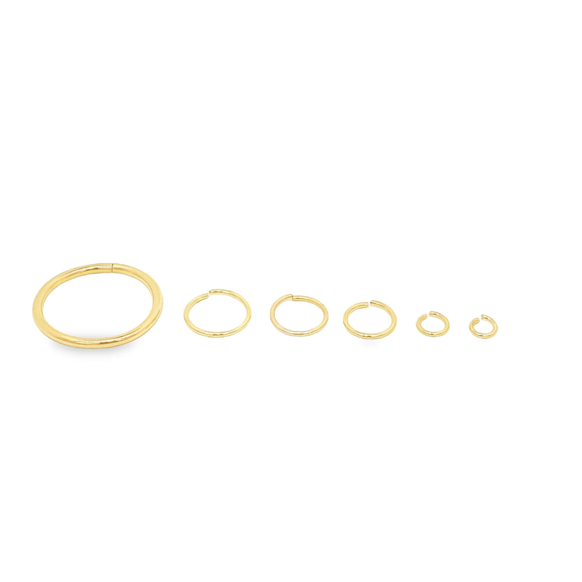 Six graduated gold jump rings line up in decreasing sizes against a plain white background.