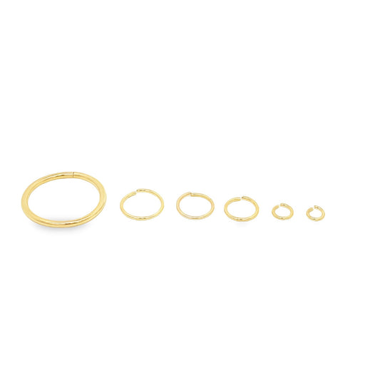 Six gold hoop nose rings of descending sizes sit in a row against a white background.