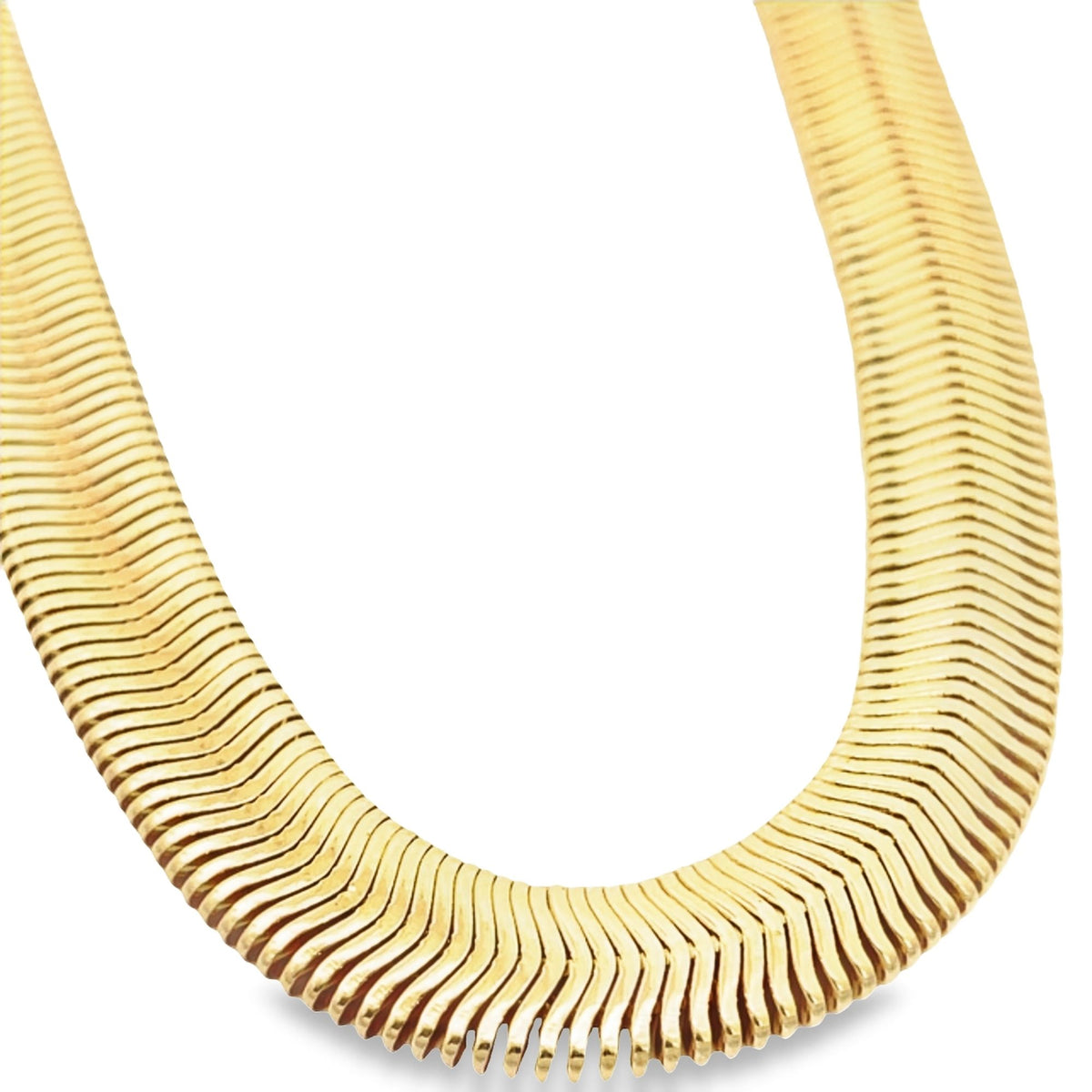A thick yellow gold herringbone necklace curves elegantly against a clean white background.