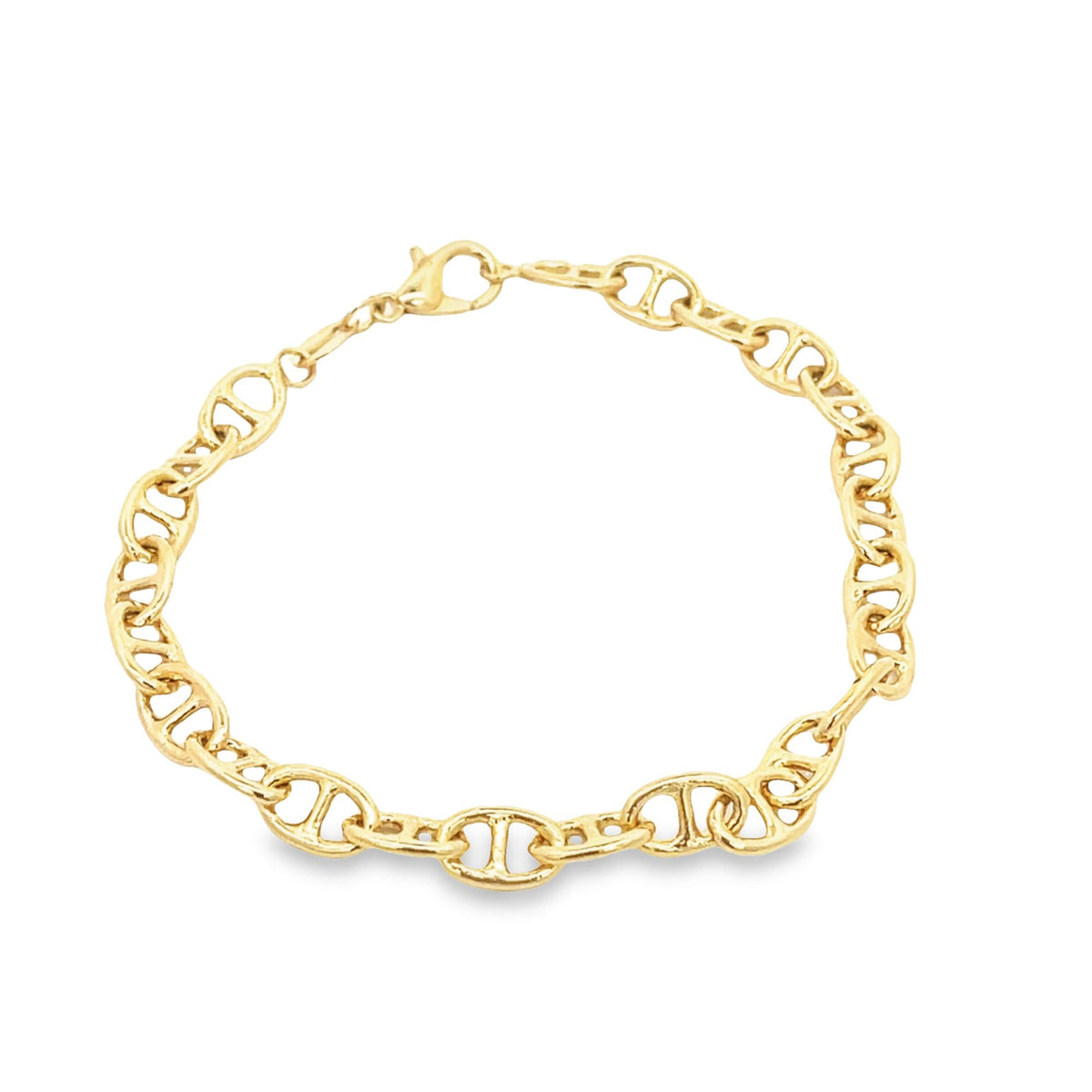 A polished gold anchor chain bracelet rests on a plain white surface.