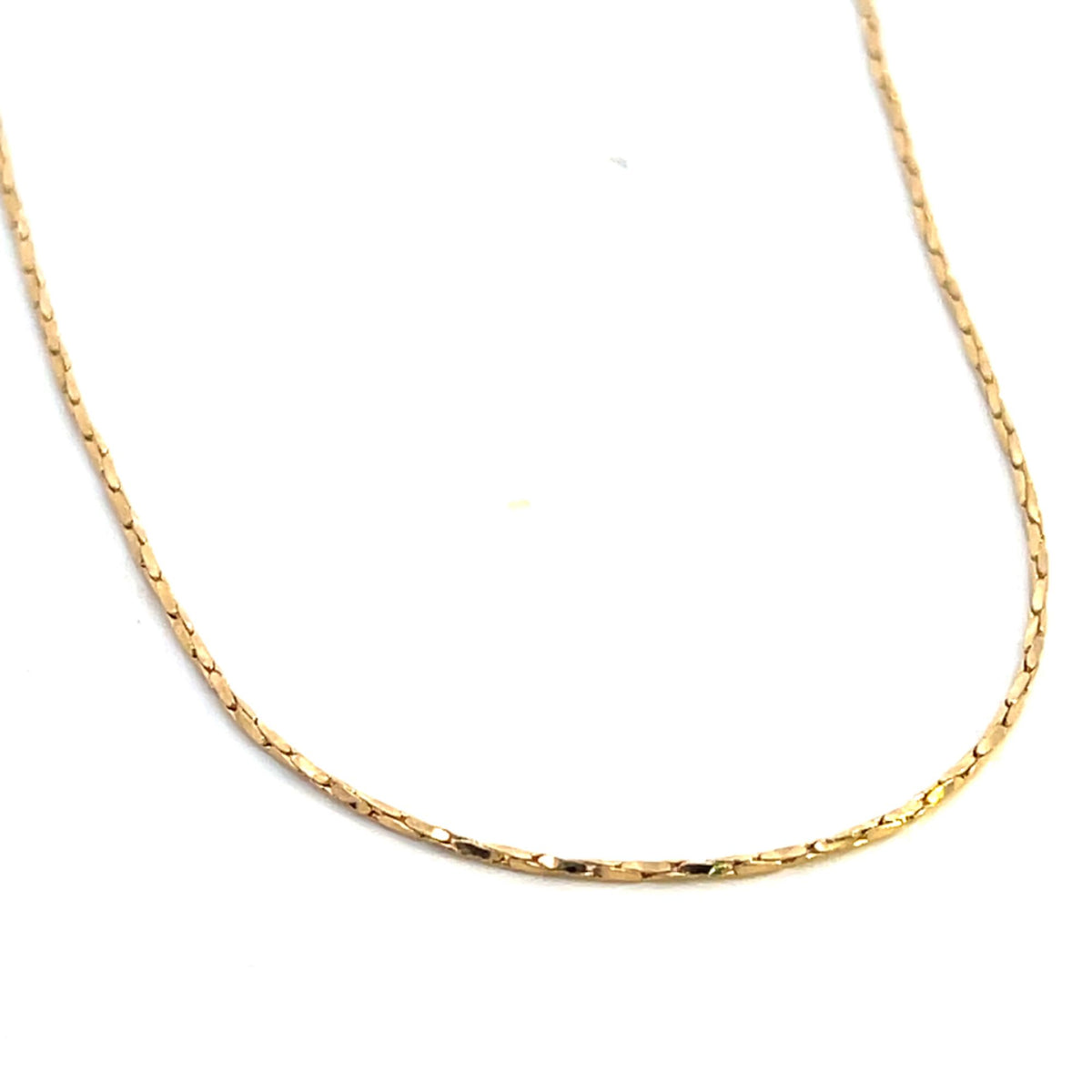 A delicate gold chain necklace drapes gracefully against a clean white background.