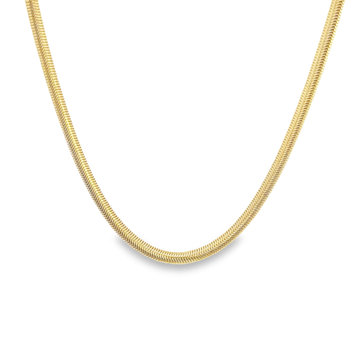 A sleek gold herringbone chain necklace curves gracefully against a plain white background.