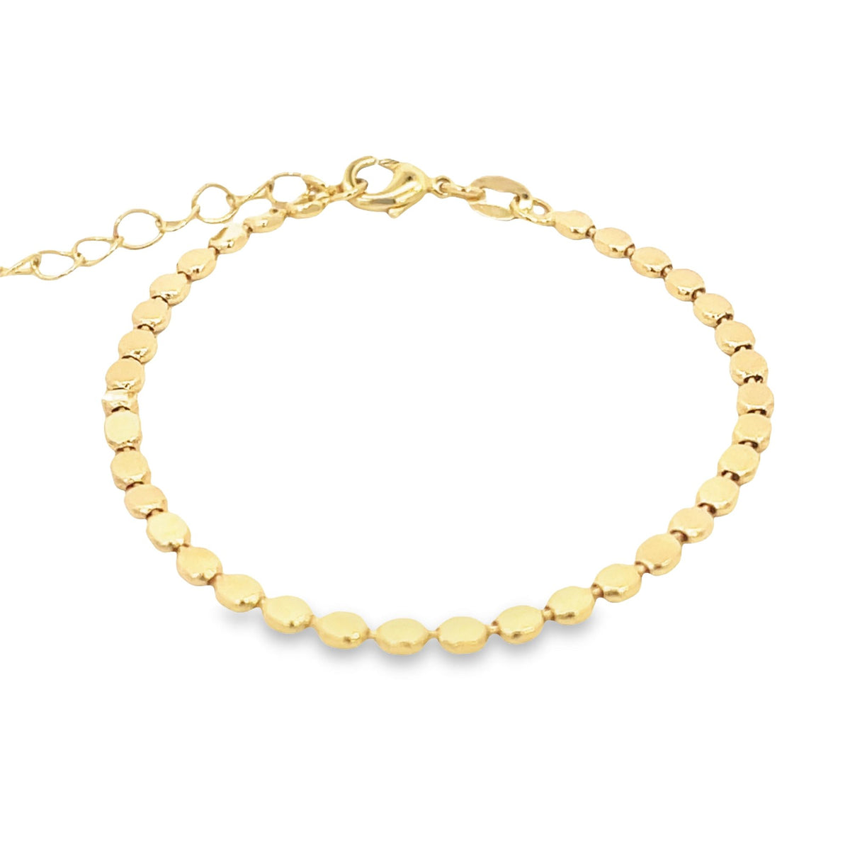 A delicate gold chain bracelet features small, flat, disc-shaped links and an adjustable extension chain against a white background.