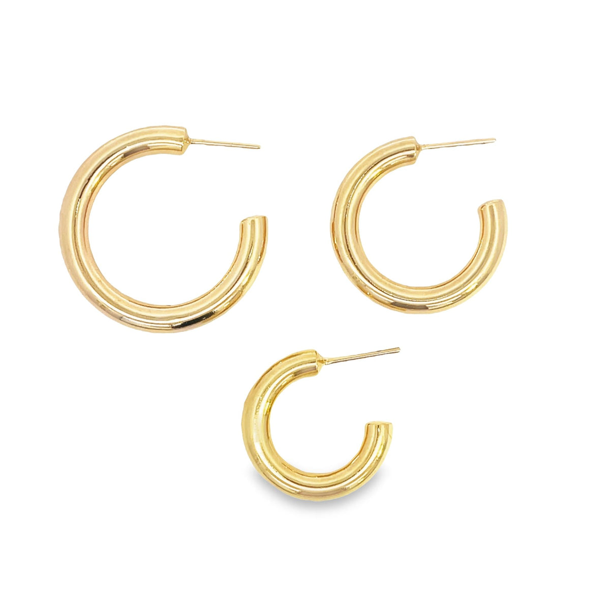 Three thick gold hoop earrings in descending sizes sit arranged on a white background.