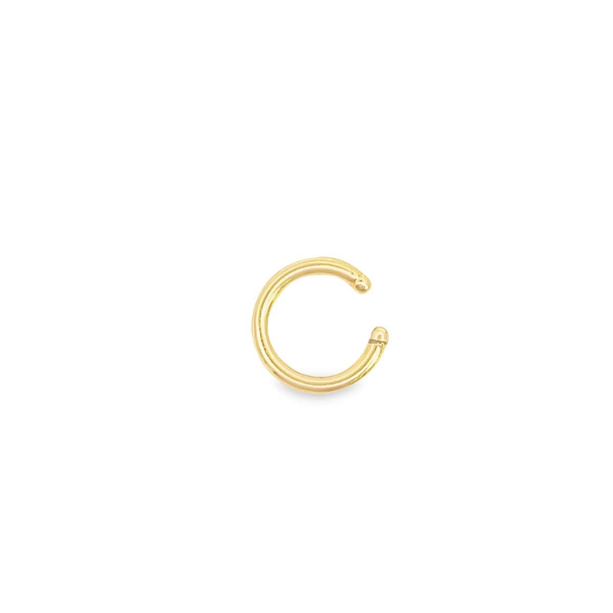 A polished gold nose ring sits centrally against a clean white background.