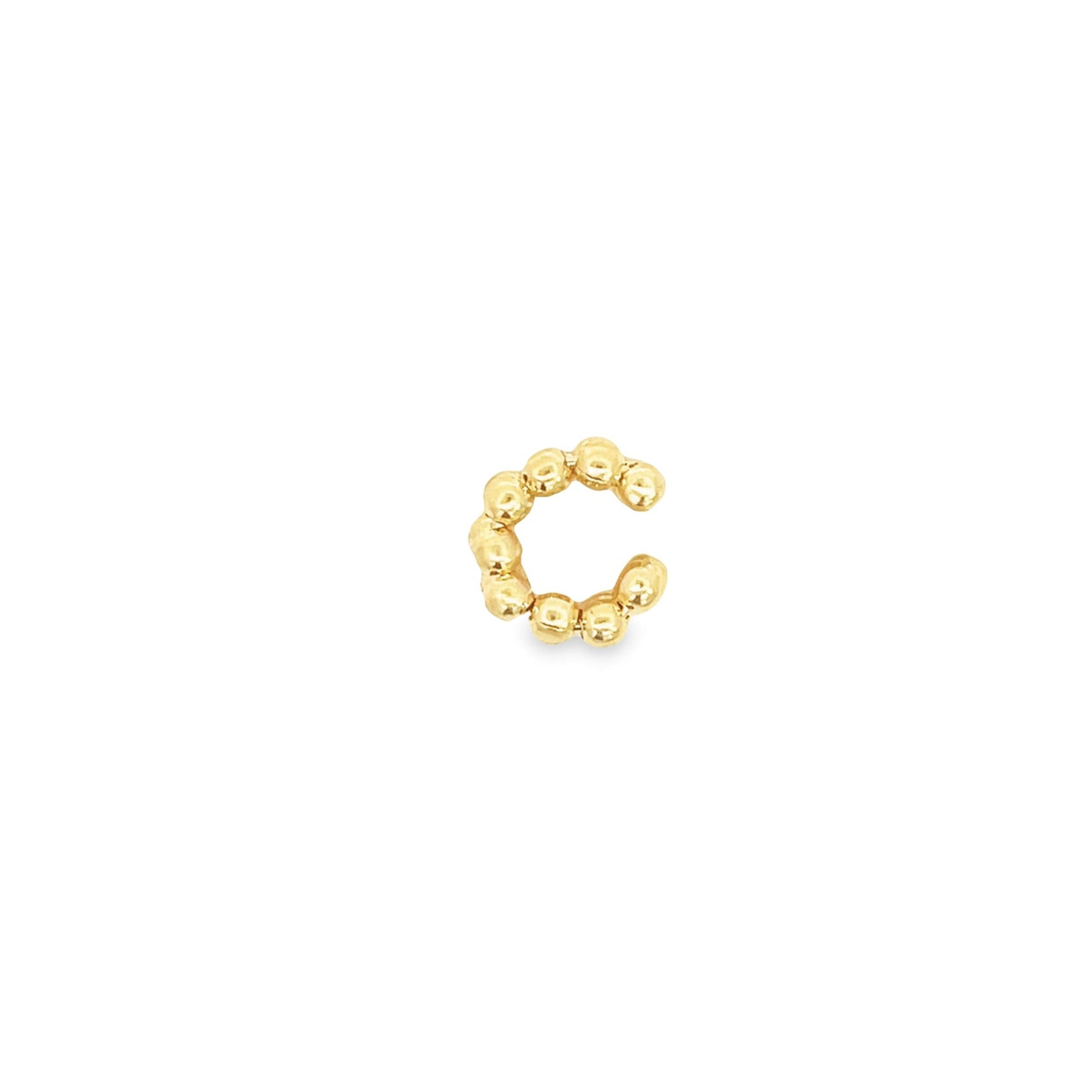 A polished gold beaded ear cuff rests against a clean white background.