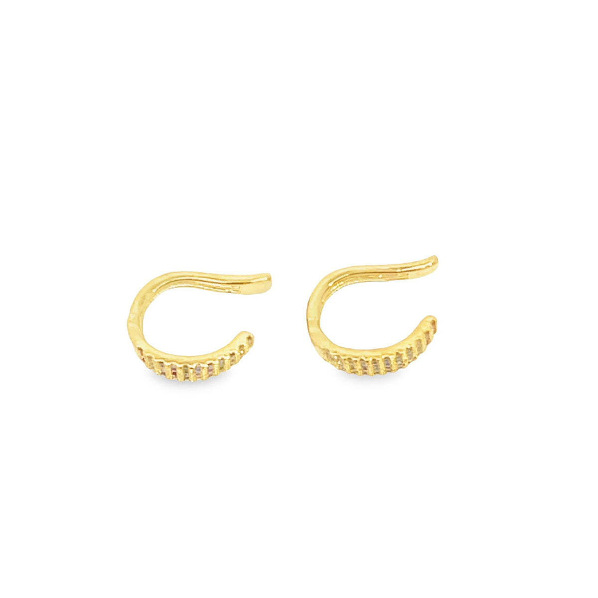 A pair of gold ear cuffs with textured gemstone settings rests against a clean white background.