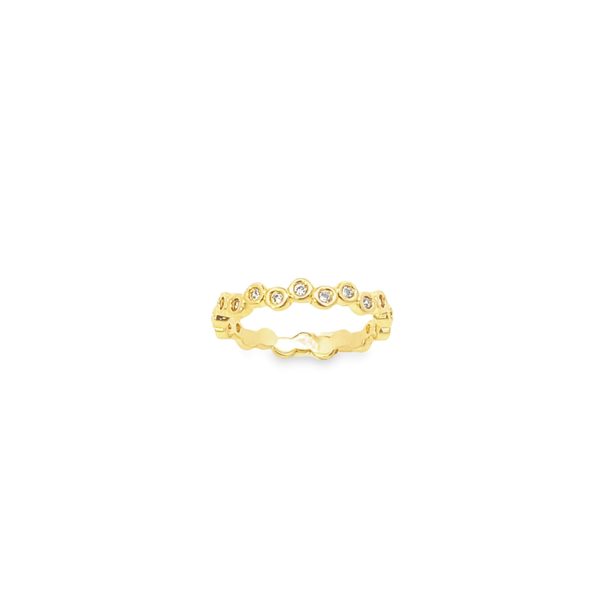A delicate gold bezel-set diamond band ring sparkles against a clean white background.