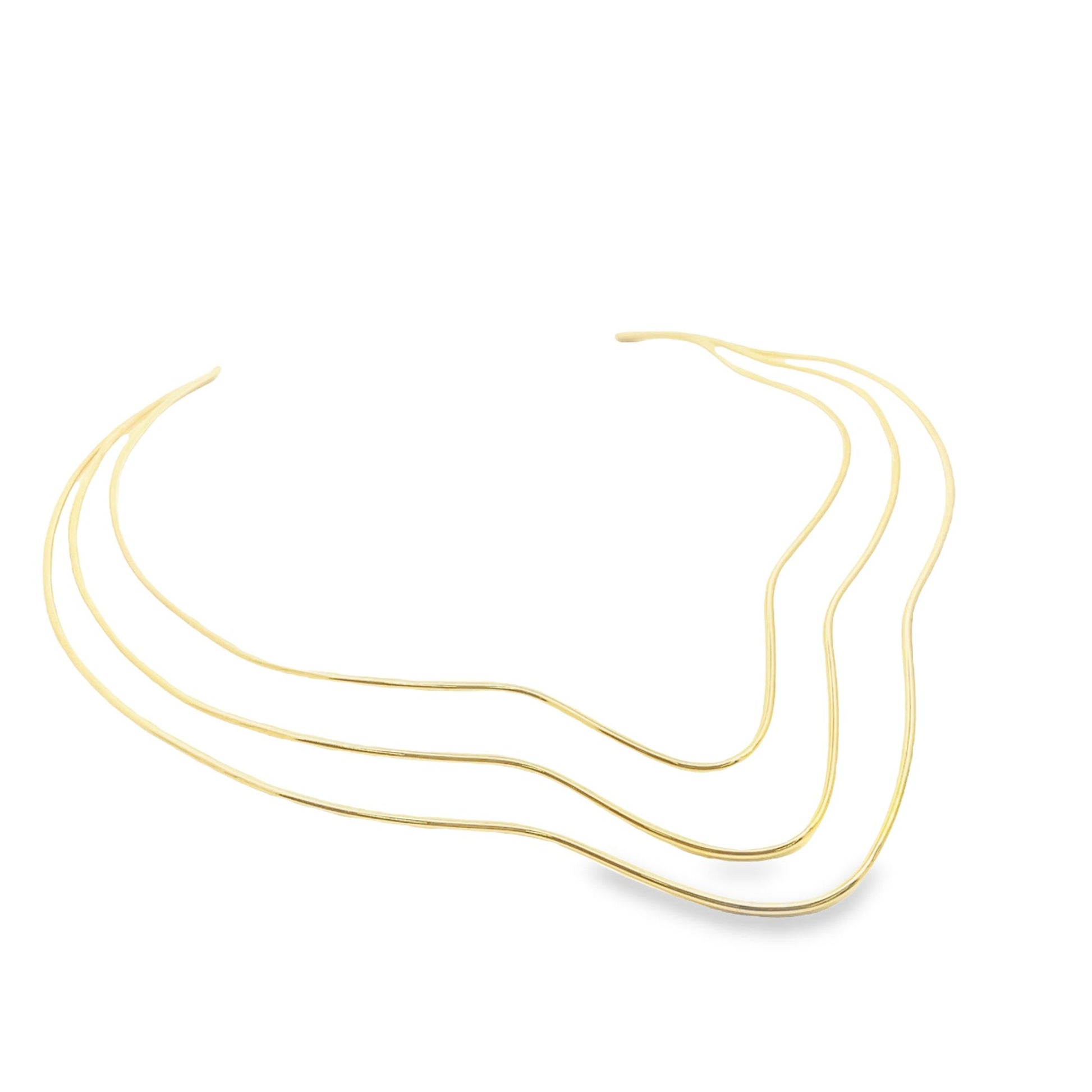 A minimalist triple-strand gold choker necklace rests in a graceful wave shape against a white background.