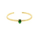 A gold cuff ring features a vibrant pear-shaped green gemstone set in the center against a clean white background.