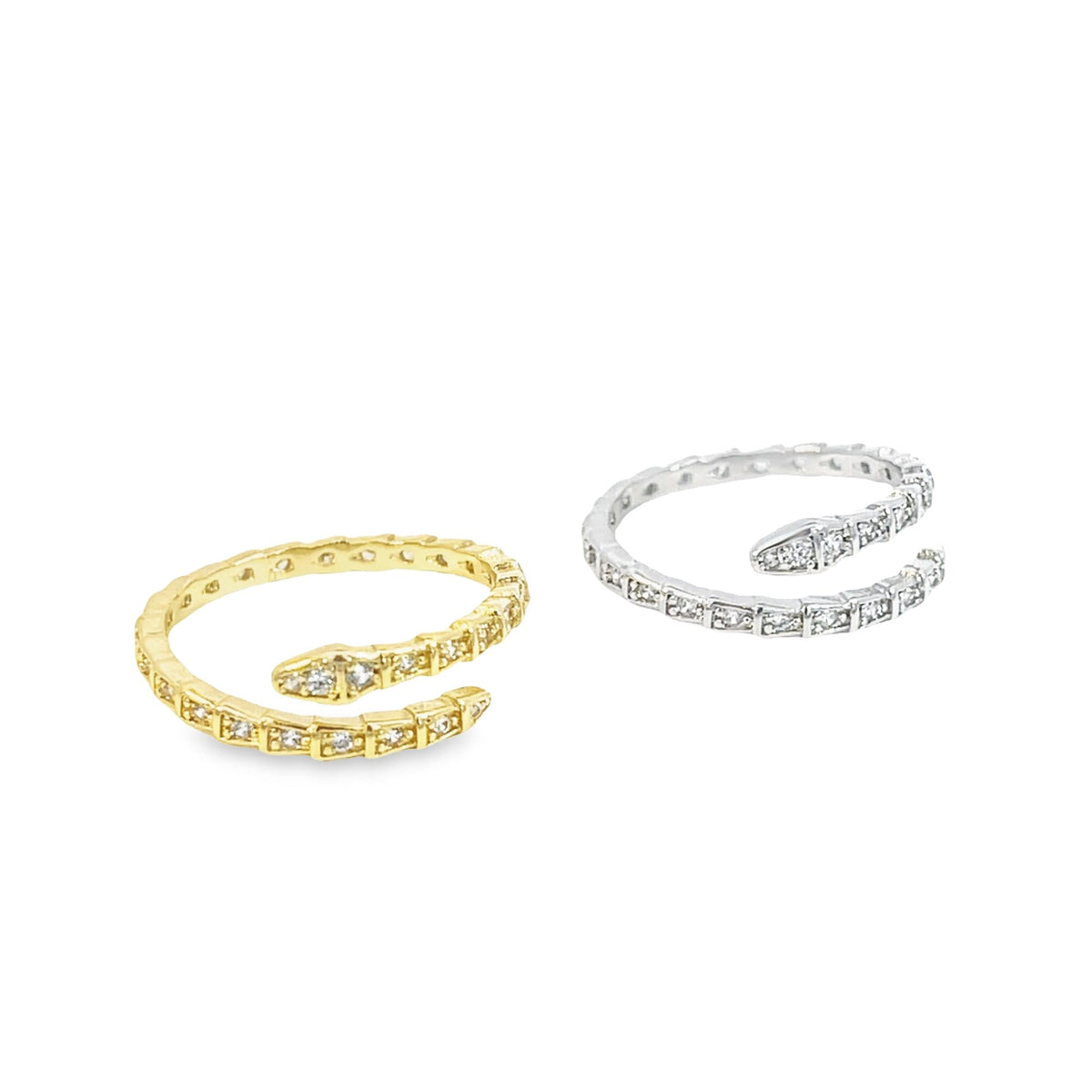 Two diamond-encrusted snake wrap rings, one in yellow gold and the other in silver, rest side by side against a white background.