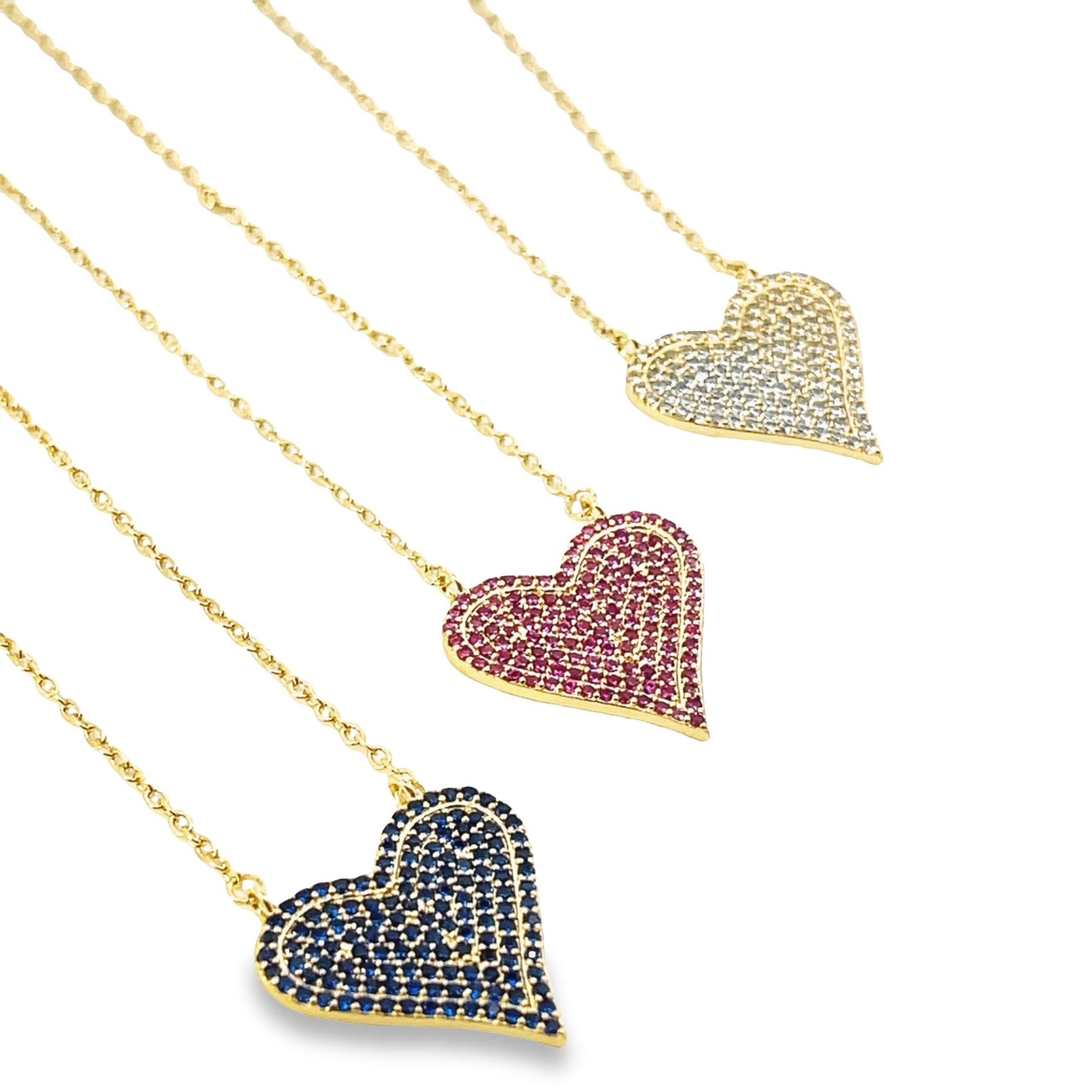 Three gold heart-shaped pendant necklaces sparkle with pavé-set white, pink, and blue crystals against a white background.