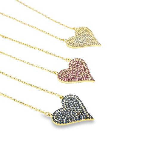 Three gold heart pendant necklaces sparkle with pavé crystals in white, pink, and blue against a white background.