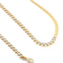 A gold tennis necklace featuring marquise-cut cubic zirconia stones lies next to a flat herringbone chain against a white background.