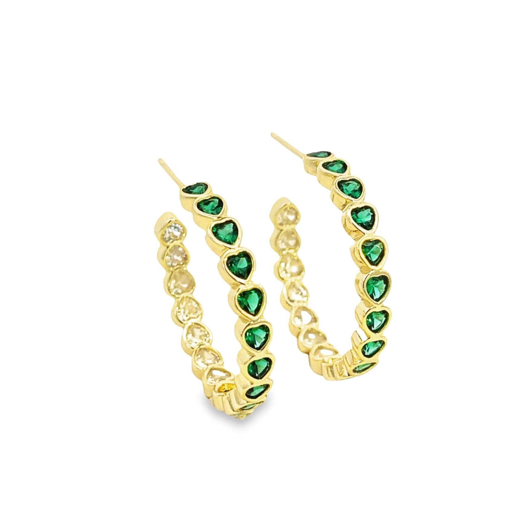 A pair of gold hoop earrings features alternating green and clear heart-shaped cubic zirconia stones set against a clean white background.