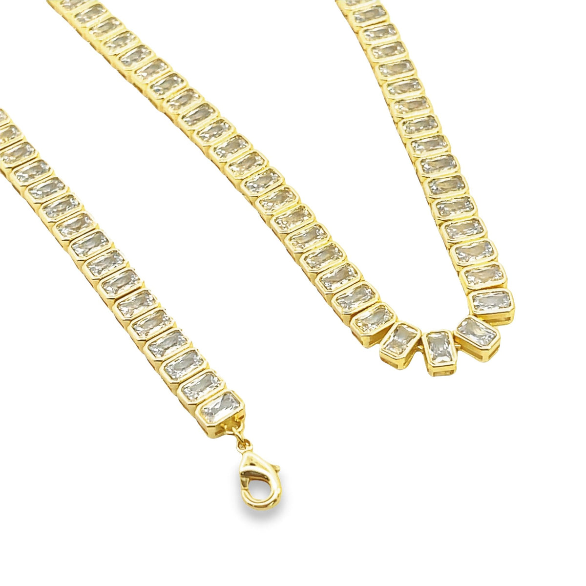 A close-up shot of a gold tennis necklace featuring sparkling emerald-cut CZ stones set in a continuous line against a clean white background.