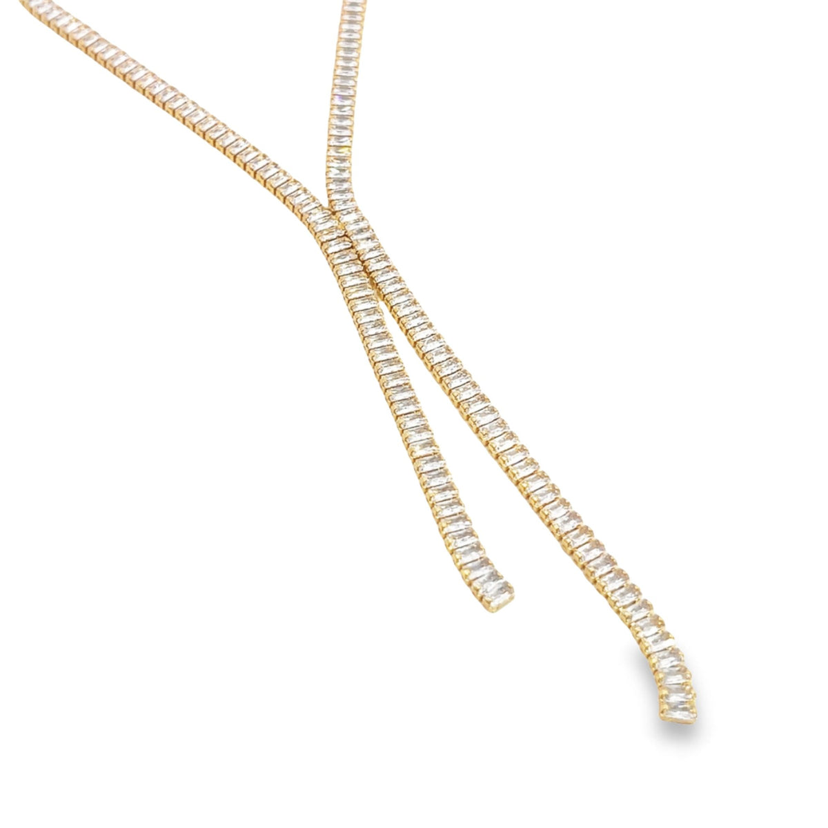 A sparkling gold lariat necklace adorned with baguette-cut diamonds drapes elegantly against a white background.