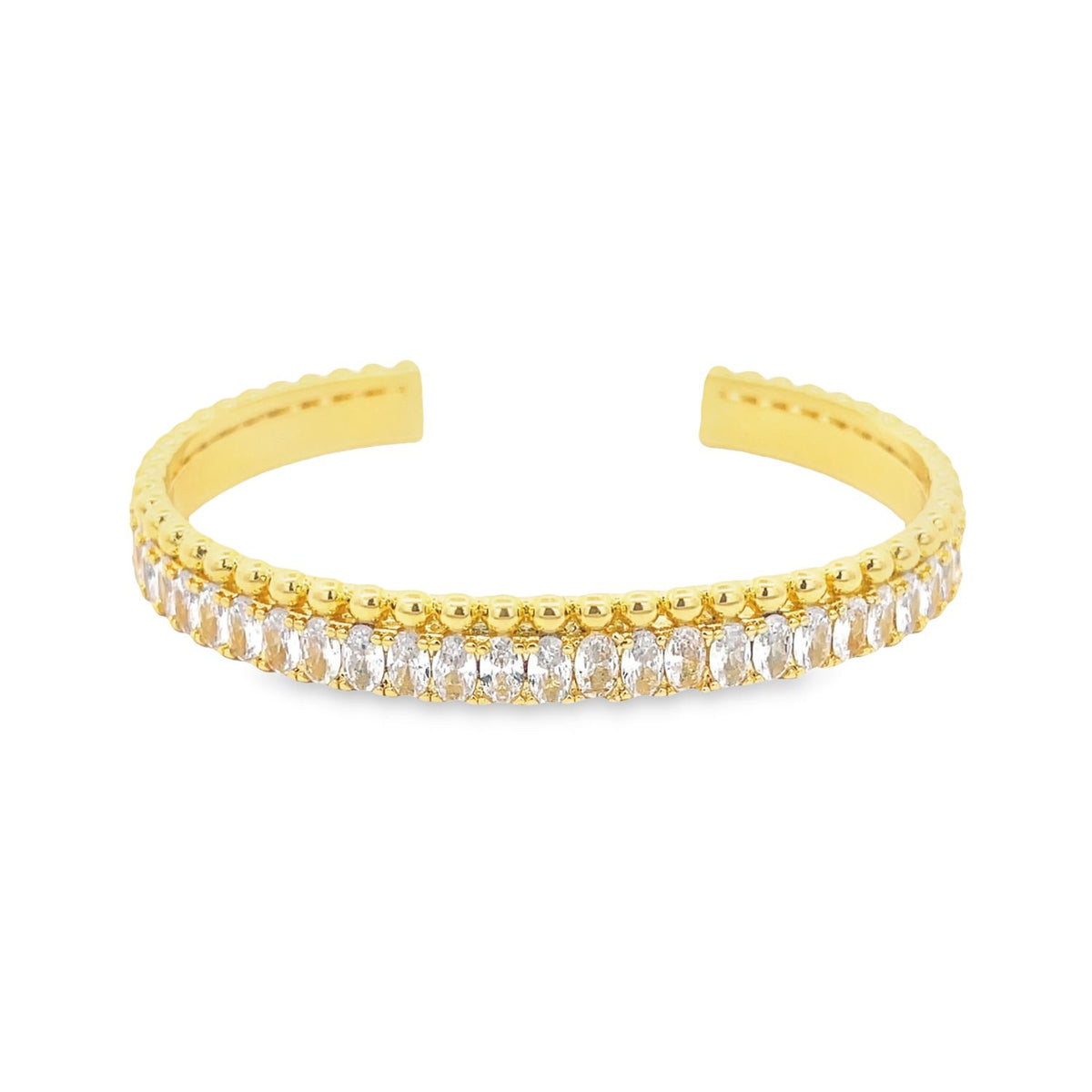 A gold cuff bracelet sparkles with a continuous row of oval-cut white cubic zirconia stones beneath a beaded edge.